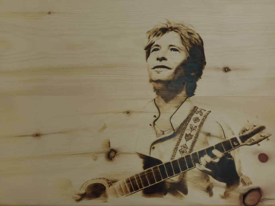 John Denver. Ritratto di John Denver su legno di cirmolo. Pirografia, 2023.. Pirografia, 2023